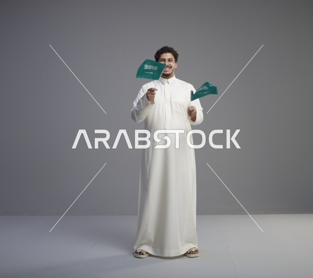 شاب سعودي مبتسم يلوح بعلم السعودية