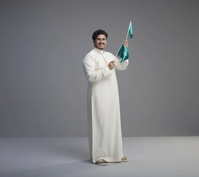 Smiling Saudi Man Waving Saudi Arabian Flags in Studio