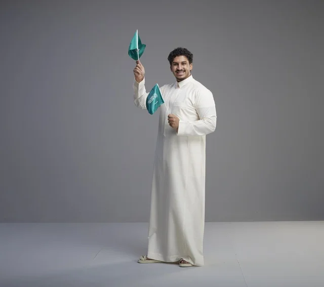 Smiling Saudi Man Holding National Flags in Studio