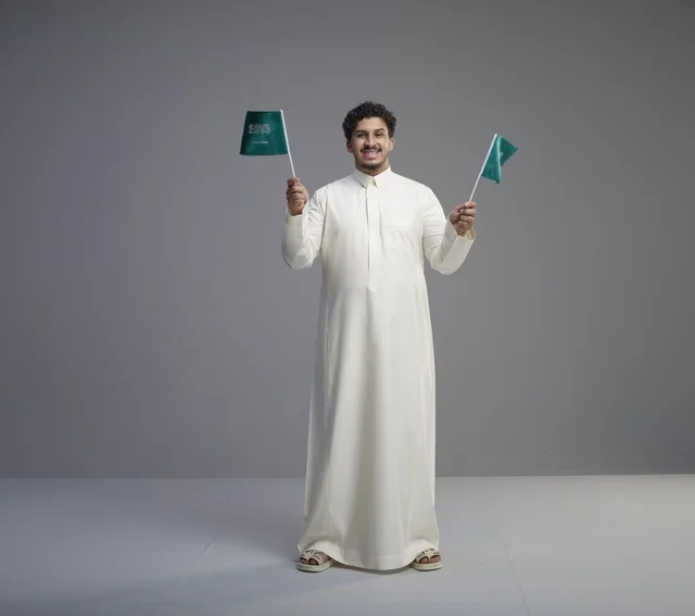 Saudi Man Wearing Thobe Holding National Flags in Studio