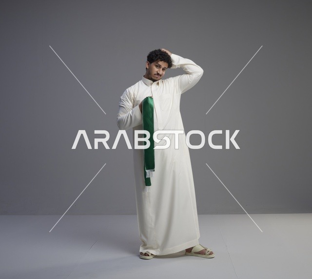 رجل سعودي بالثوب يحمل الوشاح الوطني الأخضر في الاستوديو