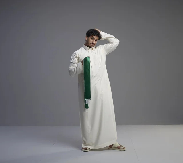 رجل سعودي بالثوب يحمل الوشاح الوطني الأخضر في الاستوديو