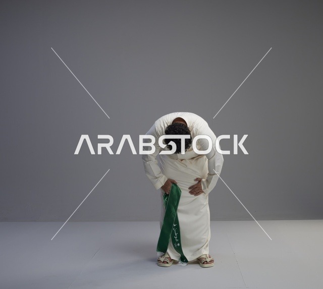 رجل سعودي بالثوب يحمل الوشاح الوطني في استوديو
