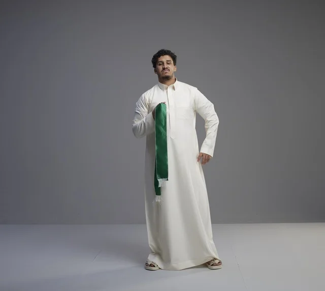 رجل سعودي بالثوب يحمل وشاح اليوم الوطني