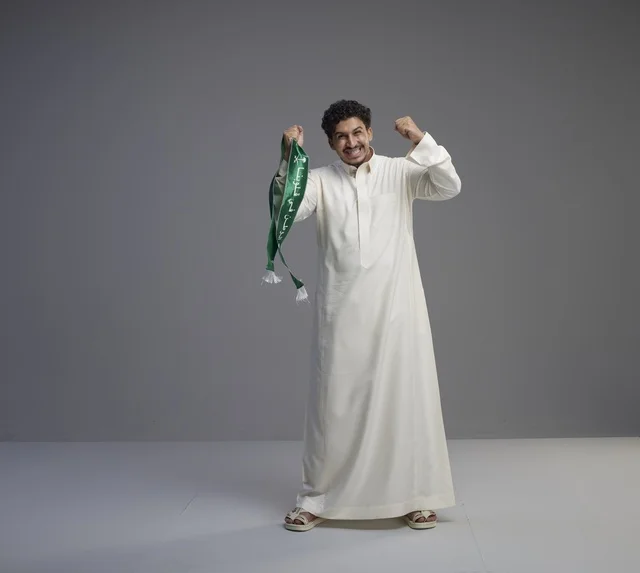 رجل سعودي بالثوب يحمل وشاحاً وطنياً في استوديو رجل سعودي بالثوب يحمل وشاحاً وطنياً في استوديو