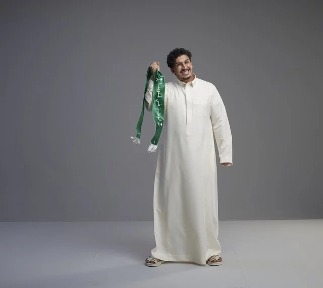 رجل سعودي يحمل وشاحاً وطنياً أخضر في استوديو التصوير رجل سعودي يحمل وشاحاً وطنياً أخضر في استوديو التصوير