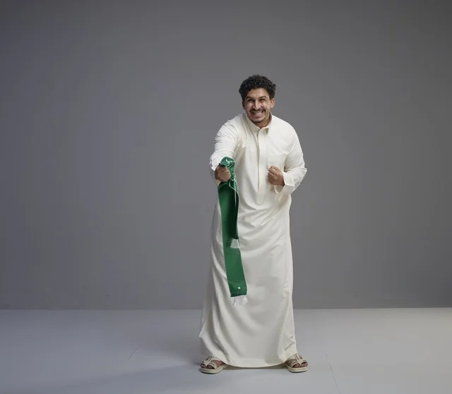 Saudi Man Holding Green National Scarf on Grey Background
