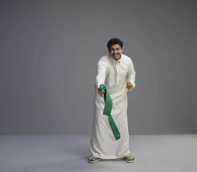 رجل سعودي يحمل وشاحاً وطنياً أخضر في الاستوديو
