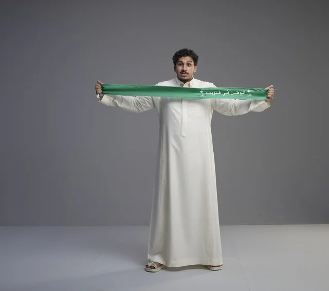 رجل سعودي يحمل وشاحاً وطنياً أخضر في الاستوديو