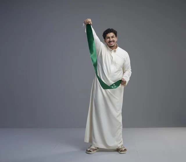 رجل سعودي يحمل وشاحاً وطنياً أخضر في الاستوديو