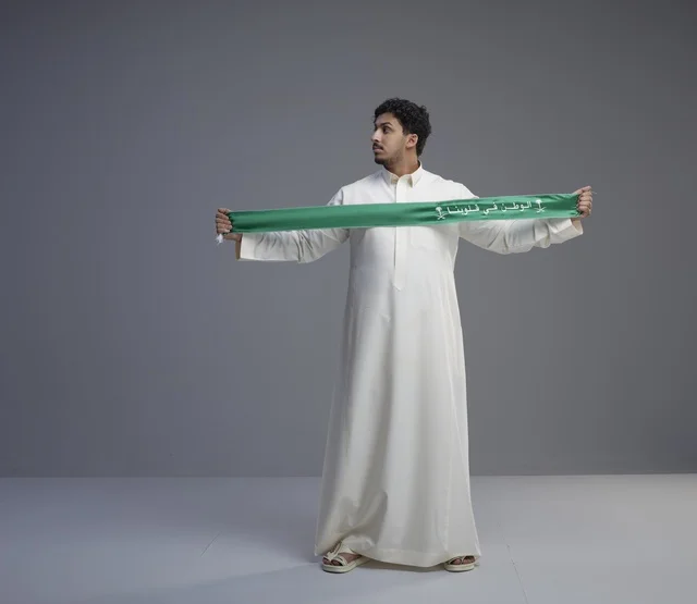 رجل سعودي يحمل وشاح اليوم الوطني الأخضر في الاستوديو