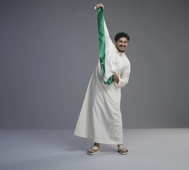 رجل سعودي يحمل وشاحاً وطنياً أخضر في الاستوديو