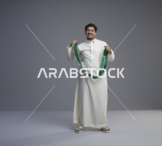 رجل سعودي بالثوب والوشاح الوطني في تصوير استوديو