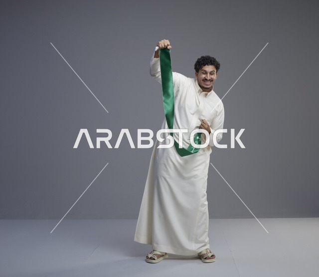 رجل سعودي بالثوب الأبيض يحمل وشاح اليوم الوطني