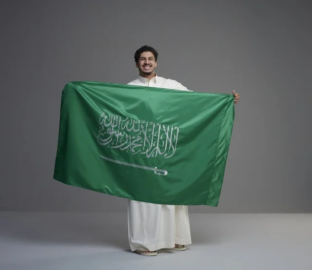 رجل سعودي يحمل علم المملكة العربية السعودية