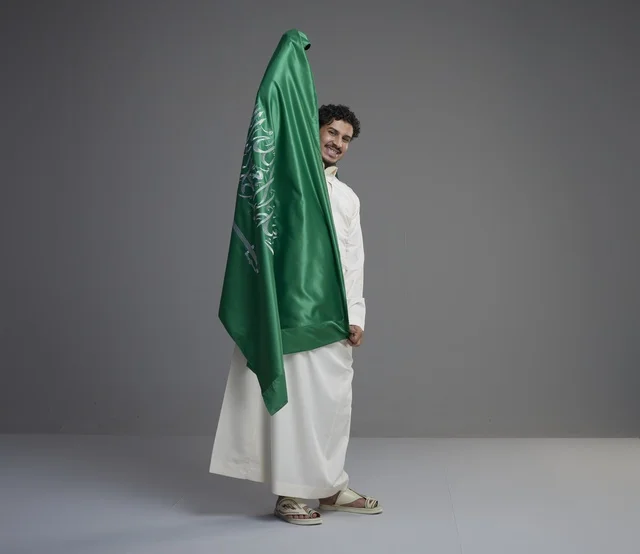رجل سعودي يحمل العلم السعودي في الاستوديو