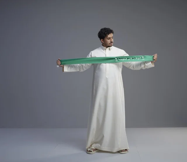 رجل سعودي بالثوب يحمل وشاحاً وطنياً أخضر رجل سعودي بالثوب يحمل وشاحاً وطنياً أخضر