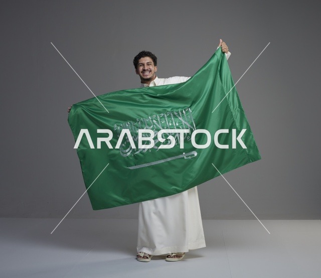 رجل سعودي يحمل العلم السعودي في الاستوديو