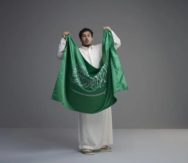 Saudi Man in Thobe Holding National Flag in Studio