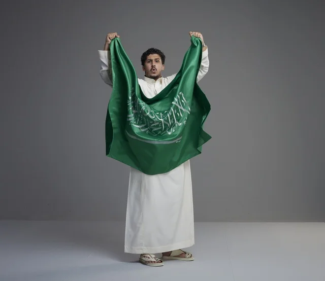 Saudi Man Holding National Flag Against Grey Background
