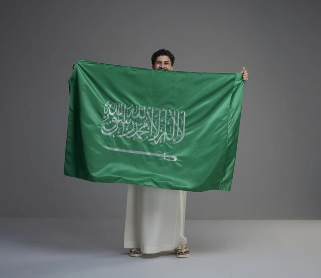 رجل سعودي يحمل العلم الوطني السعودي في الاستوديو