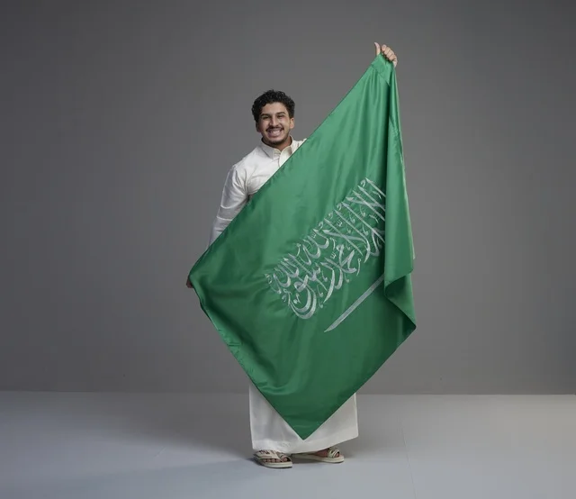 رجل سعودي يحمل علم المملكة العربية السعودية في استوديو
