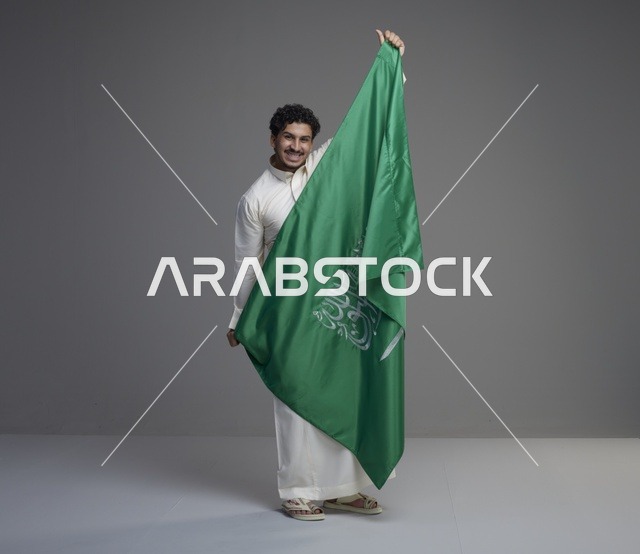 رجل سعودي يحمل العلم السعودي في الاستوديو