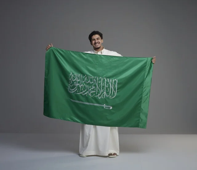 رجل سعودي يحمل علم المملكة العربية السعودية