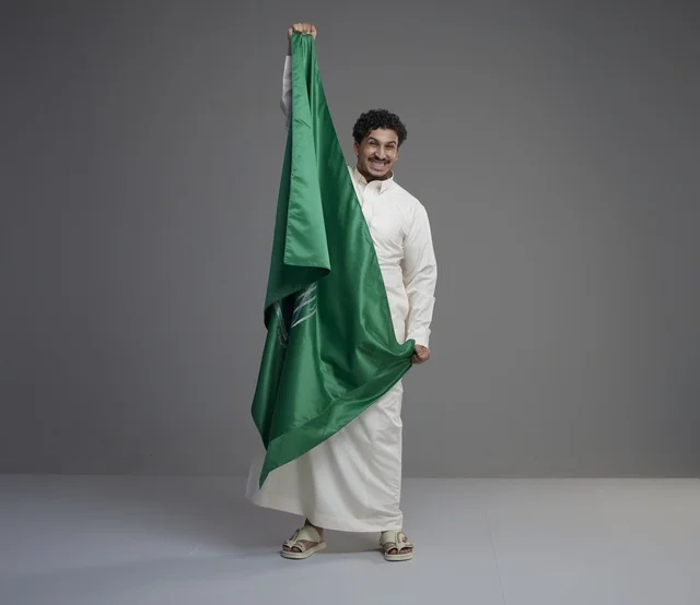 رجل سعودي يحمل العلم الوطني في الاستوديو