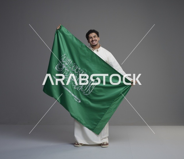 رجل سعودي يحمل علم المملكة العربية السعودية