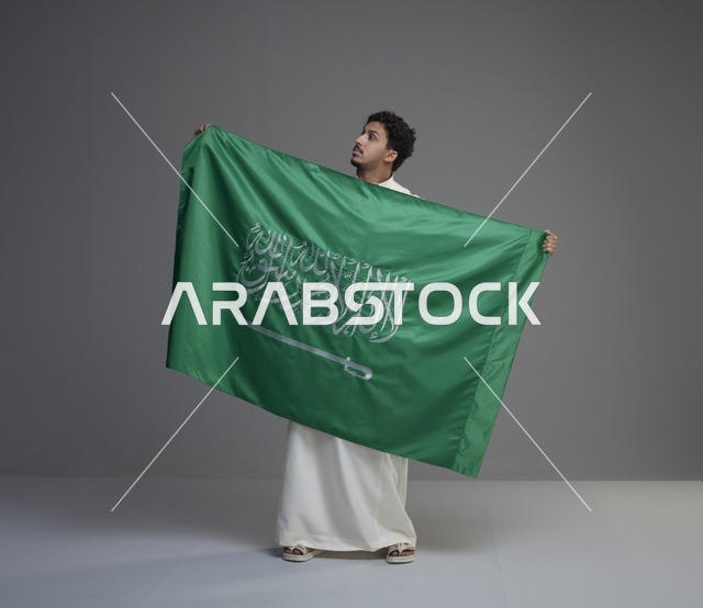 رجل سعودي يحمل علم المملكة العربية السعودية