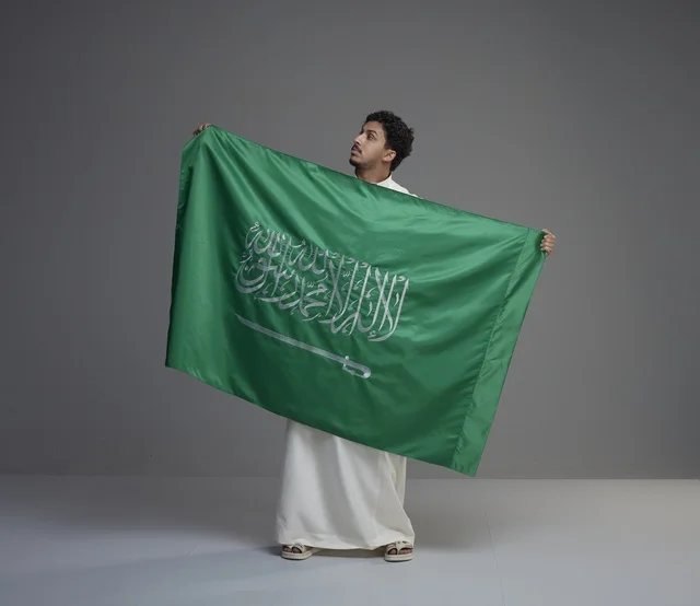 رجل سعودي يحمل علم المملكة العربية السعودية