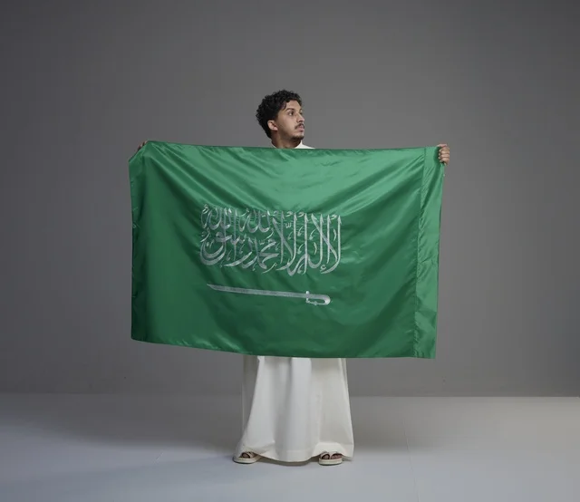 رجل سعودي يحمل علم المملكة العربية السعودية في استوديو