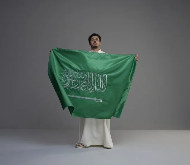 Saudi Man Holding Saudi Arabian Flag in Studio