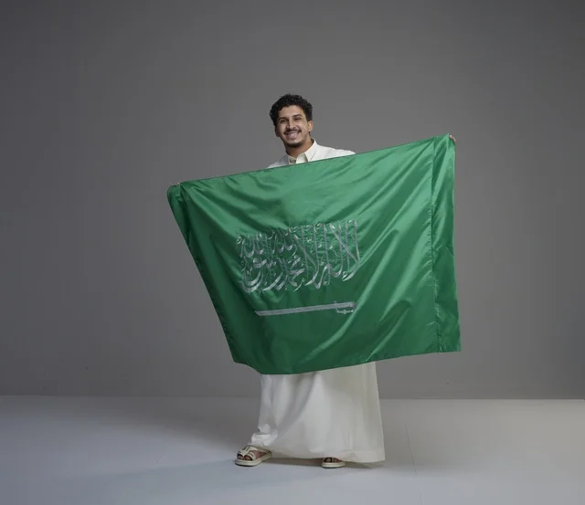 رجل سعودي يحمل علم المملكة العربية السعودية
