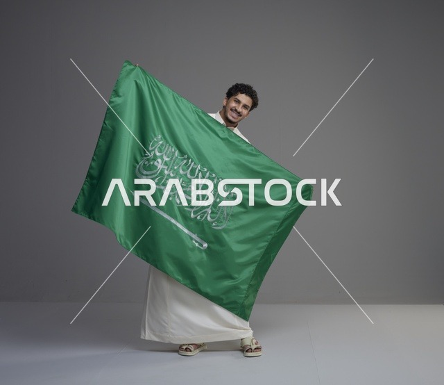 رجل سعودي يحمل العلم السعودي في استوديو