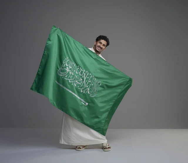 رجل سعودي يحمل العلم السعودي في استوديو