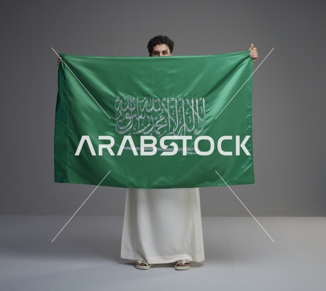 رجل سعودي يحمل علم المملكة العربية السعودية