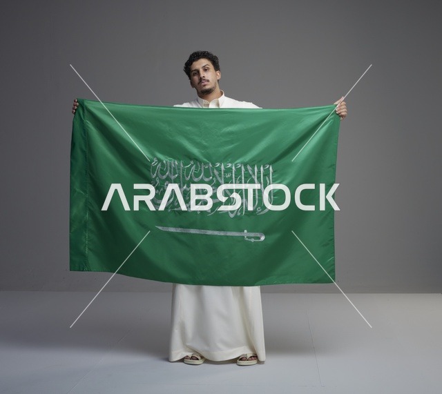 رجل سعودي يحمل علم المملكة العربية السعودية