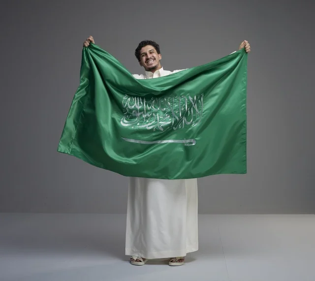 رجل سعودي يحمل العلم الوطني في الاستوديو