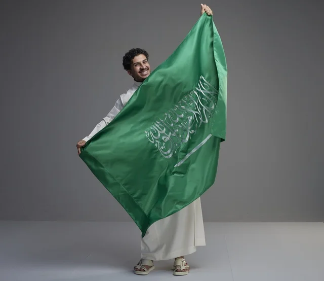 رجل سعودي يحمل علم المملكة العربية السعودية