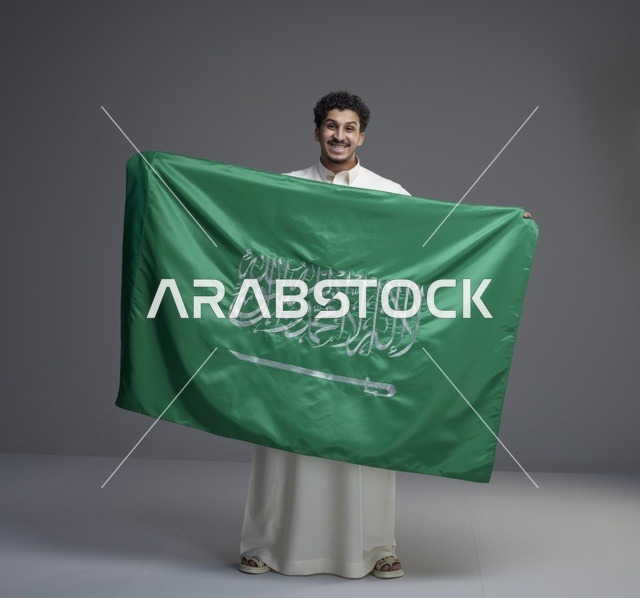 رجل سعودي يحمل العلم السعودي في الاستديو