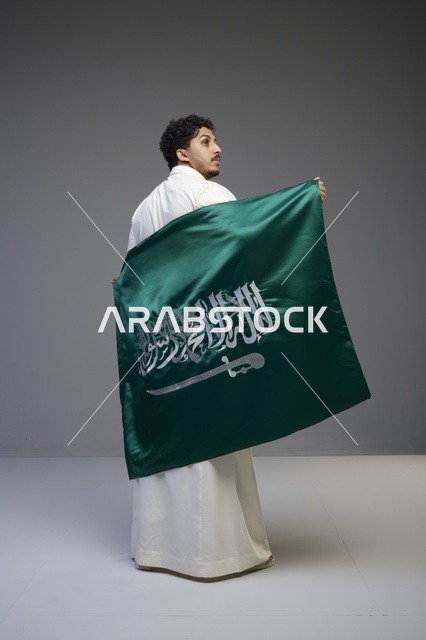 رجل سعودي يحمل علم المملكة العربية السعودية