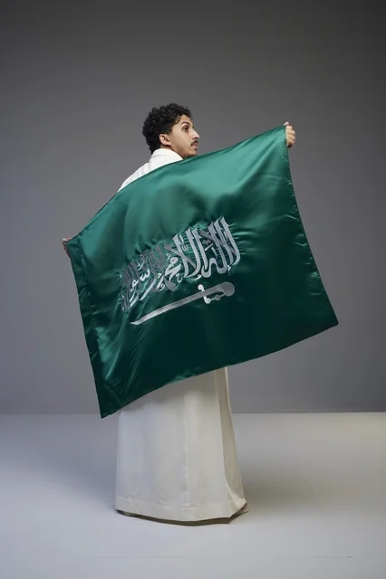 رجل سعودي يحمل علم المملكة العربية السعودية