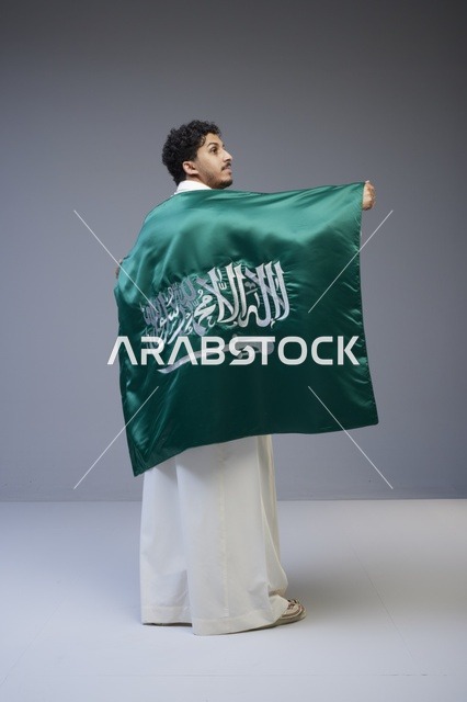 رجل سعودي يحمل علم المملكة العربية السعودية في استوديو