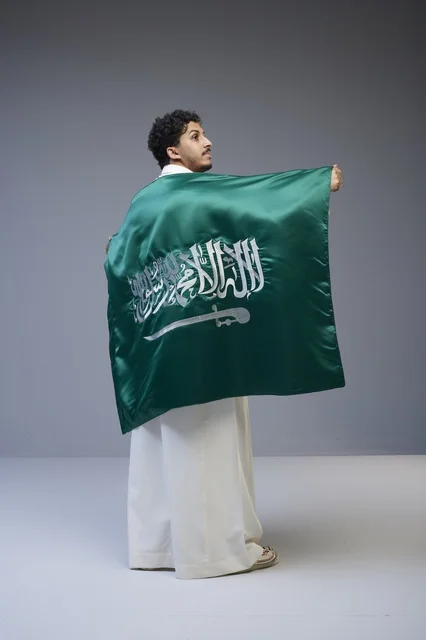 رجل سعودي يحمل علم المملكة العربية السعودية في استوديو