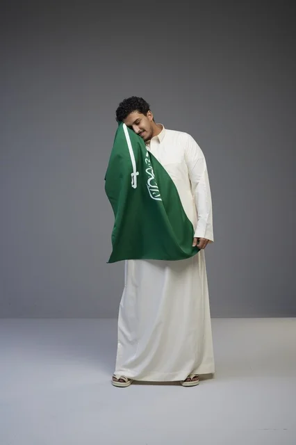 مواطن سعودي يحمل علم المملكة العربية السعودية في استوديو