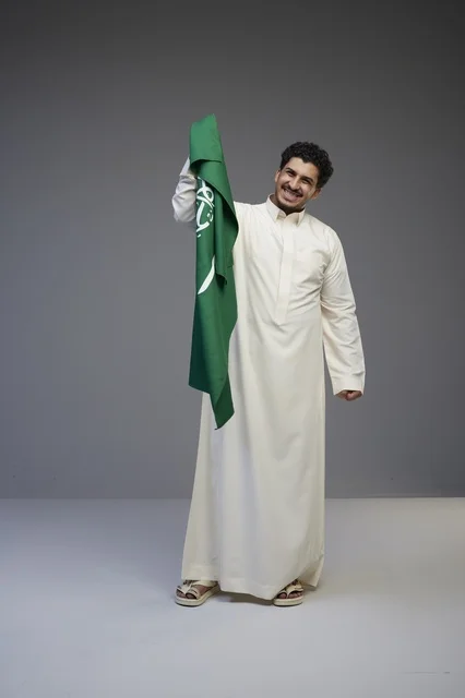 Saudi Man Holding Saudi Arabian Flag in Studio