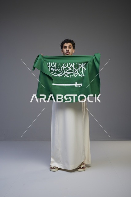 رجل سعودي يحمل علم المملكة العربية السعودية في استوديو