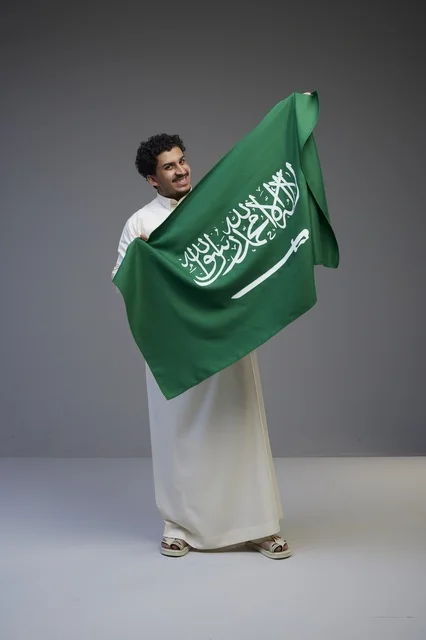 رجل سعودي يحمل العلم الوطني السعودي في الاستوديو